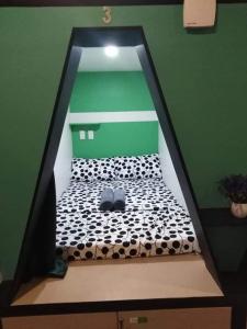 Bett in einem Zimmer mit grüner Wand in der Unterkunft Napsule Suites in Davao City