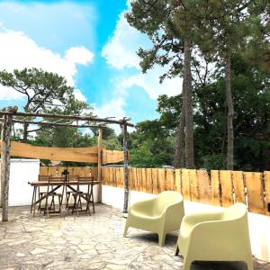 een patio met een tafel en stoelen en een houten hek bij Appart sous les pins 600m plage in Longeville-sur-Mer