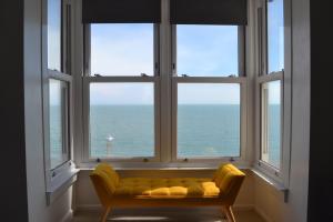 a yellow couch in a room with three windows at Fairlight View in Folkestone