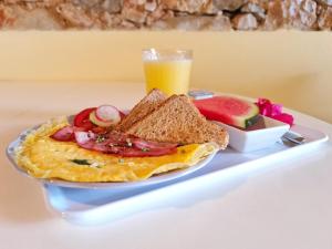 a breakfast plate with an omelet and toast and a glass of juice at Sunlight House in Faro