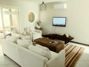 sala de estar con sofás blancos y TV de pantalla plana en Casa com piscina e churrasq na Praia de Camburí, en São Sebastião