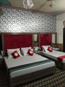 a bedroom with two beds with red pillows at Royal palace hotel in Lahore