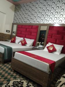 two beds with red headboards in a hotel room at Royal palace hotel in Lahore