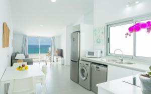cocina blanca con fregadero y lavadora en El Ático Del Mar 5B, en Las Palmas de Gran Canaria