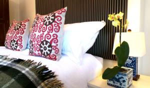 Una cama con almohadas rojas y blancas y una mesa con una planta. en Antler Guest House, en Edimburgo