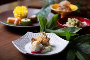 une assiette de nourriture sur une table avec d’autres assiettes de denrées alimentaires dans l'établissement Kutsukake Stay Naka-Karuizawa, à Karuizawa