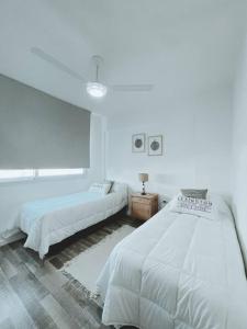 una camera da letto bianca con due letti e una finestra di Duplex Terrada a Bahía Blanca