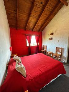 a bedroom with a red bed with two chairs and a window at Bla Lodge in El Calafate