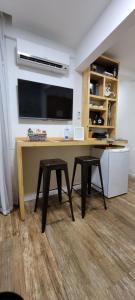 里約熱內盧的住宿－Apezinho.Loft，一张桌子,两张凳子,墙上有一台电视机