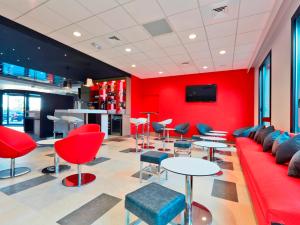 a red room with a couch and tables and chairs at Première Classe Lyon - Saint Priest Eurexpo in Saint-Priest