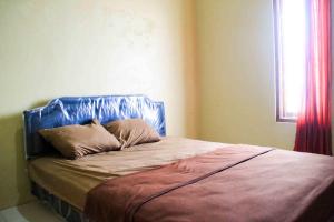 uma cama com uma cabeceira azul num quarto em Puri Karomah Syariah RedPartner em Lamongan