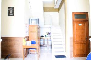 a room with a staircase with a microwave and a kitchen at Puri Karomah Syariah RedPartner in Lamongan