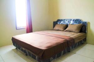 a bed in the corner of a room with a window at Puri Karomah Syariah RedPartner in Lamongan