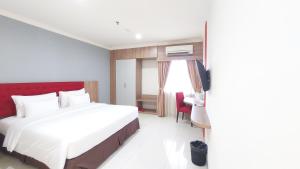 una camera con un grande letto bianco e una testiera rossa di Moritz Hotel RSAB Harapan Kita a Giacarta