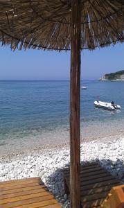 a beach with an umbrella and a boat in the water at Holiday House Villa Neda in Utjeha