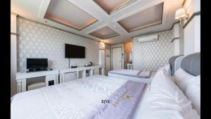 a bedroom with two beds and a flat screen tv at Yeosu Beach Hotel in Yeosu