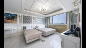 a bedroom with two beds and a television in it at Yeosu Beach Hotel in Yeosu