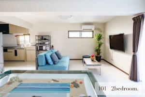 a living room with a blue couch and a tv at HOTEL FIT IN ISHIGAKIJIMA 新築2021年4月OPEN セキュリティ万全 セルフチェックイン -SEVEN Hotels and Resorts- in Ishigaki Island