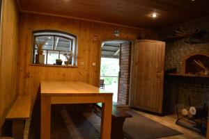 a room with a wooden table and a fireplace at Viesu nams Klāņas in Engure