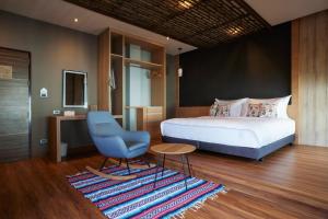 a bedroom with a bed and a blue chair at Sand Dollar Boutique Hotel in Bang Sare