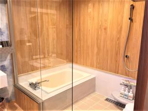 La salle de bains est pourvue d'une baignoire et d'une douche. dans l'établissement IBARA DENIM HOTELS 舞鶴楼, à Ibara