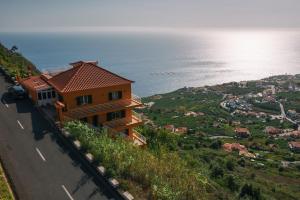a house on a hill next to the ocean at Sunset House in Arco da Calheta