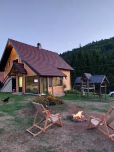two chairs and a fire in front of a house at Brvnara Miris Bora - sa bazenom - in Šljivovica