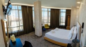 a bedroom with a large bed and a room with windows at Hotel CITY Petrich in Petrich