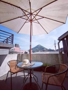 a table and chairs with an umbrella on a balcony at Jiufen Back Yard Homestay in Jiufen