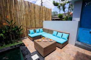 um pátio com um sofá azul e uma mesa em Lacrissa Bali em Kerobokan