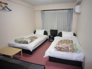a hotel room with two beds and a window at Pension Kitashirakawa in Kyoto
