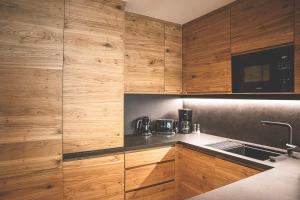 una cocina con armarios de madera y fregadero en Hotel & Appartements Alpenresidenz Viktoria en Neustift im Stubaital