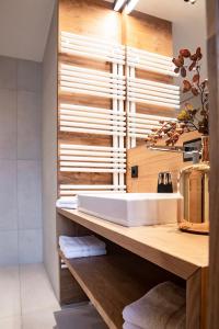 La salle de bains est pourvue d'un lavabo blanc sur un comptoir en bois. dans l'établissement Hotel & Appartements Alpenresidenz Viktoria, à Neustift im Stubaital