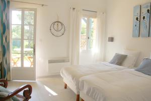 ein weißes Schlafzimmer mit 2 Betten und einem Fenster in der Unterkunft Au Petit Bernerot - Les gîtes de l'Arbre Voyageur in Eauze + 37 Fotos