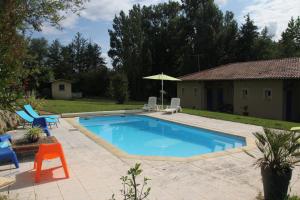 ein Swimmingpool mit zwei Stühlen und einem Sonnenschirm in der Unterkunft Au Petit Bernerot - Les gîtes de l'Arbre Voyageur in Eauze