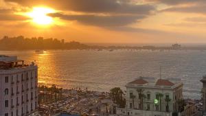 Blick auf eine Stadt mit Sonnenuntergang über dem Wasser in der Unterkunft Royal Luxury Apartment with Gorgeous Sea View in Alexandria