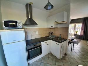 a kitchen with white cabinets and a microwave at Idéalement situé, spacieux et agréable, parking gratuit et classé 3 étoiles in Mende