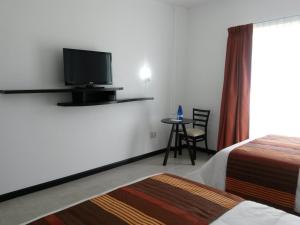 a hotel room with a tv and a bed and a table at Hotel Osalle Inn in Chignahuapan