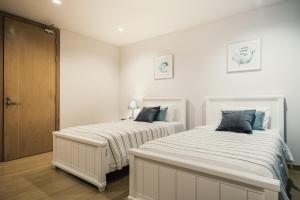two beds in a bedroom with white walls at Sandbox beachfront villa2 in Bang Lamung