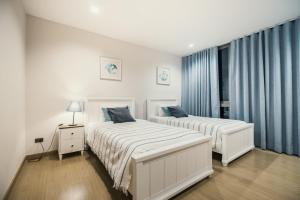 two beds in a bedroom with blue curtains at Sandbox beachfront villa2 in Bang Lamung