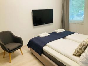 a bedroom with a bed and a chair and a television at ZAWIA APARTMAN in Balatonföldvár