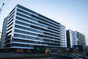wysoki budynek z zaparkowanymi przed nim samochodami w obiekcie D Apartments Centrum Jurowiecka III w mieście Białystok