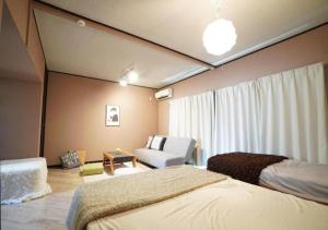 een slaapkamer met 2 bedden en een bank en een stoel bij Cross Villa Yoshizuka in Fukuoka