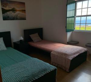 een kamer met 2 bedden en een raam bij Adega da Prainha in Prainha de Baixo