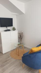 a living room with a blue couch and a glass table at Studio L'orée du port in Saint-Valery-en-Caux