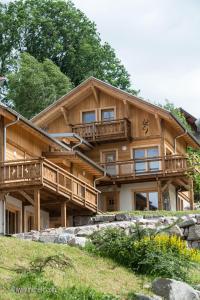 une grande maison en bois avec une terrasse sur une colline dans l'établissement Les Adrets, à Gérardmer