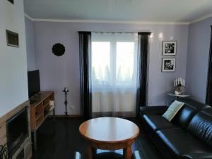 a living room with a black leather couch and a table at Apartament Mysłakowice in Mysłakowice