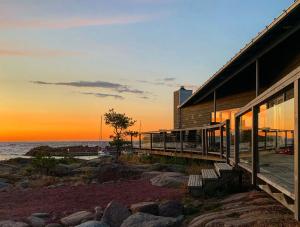 a building with benches next to the ocean at sunset at Klipphus 3 Guerilla Hotel - Geta, Åland in Geta