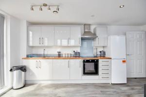 una cucina con armadietti bianchi e frigorifero bianco di Stylish 2 Bed Apartment with Free parking, close to City Centre by Hass Haus a Manchester