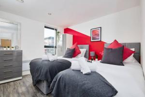 2 letti in una camera da letto con parete rossa di Stylish 2 Bed Apartment with Free parking, close to City Centre by Hass Haus a Manchester